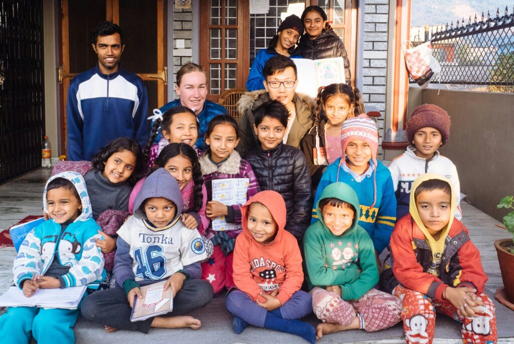 A group of children dressed in colorful winter clothing poses together outdoors, showcasing a warm and cheerful atmosphere.